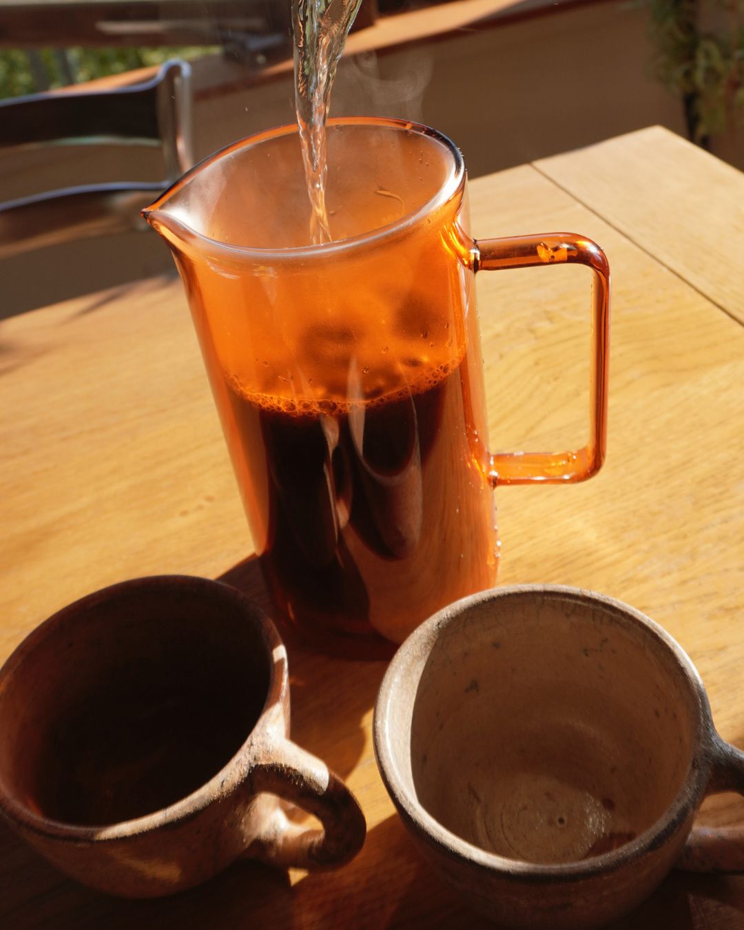 Hot water being poured into a glass French press coffee maker before brewing coffee