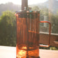 Glass French press coffee maker with stainless steel plunger on a sunlit kitchen table