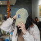 Woman adjusting the curved visor of a beige Laidrey baseball cap with an unstructured, low-profile fit