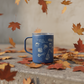 Laidrey camp mug sitting on a stone ledge surrounded by fallen autumn leaves