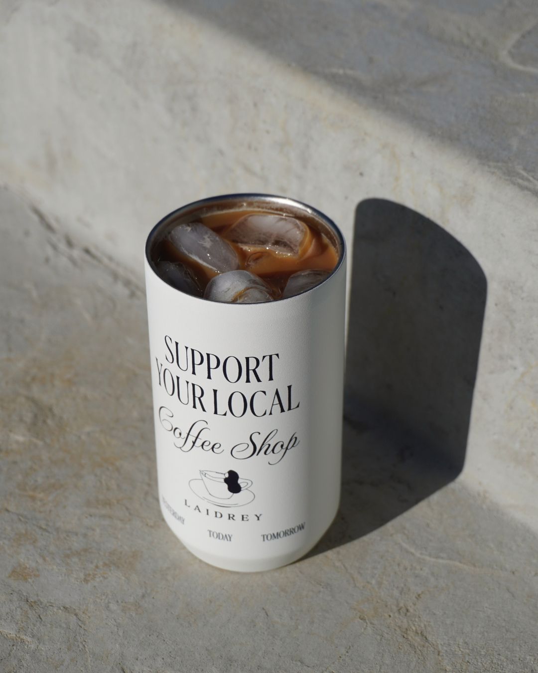 Reusable coffee tumbler being held with support your local coffee shop design